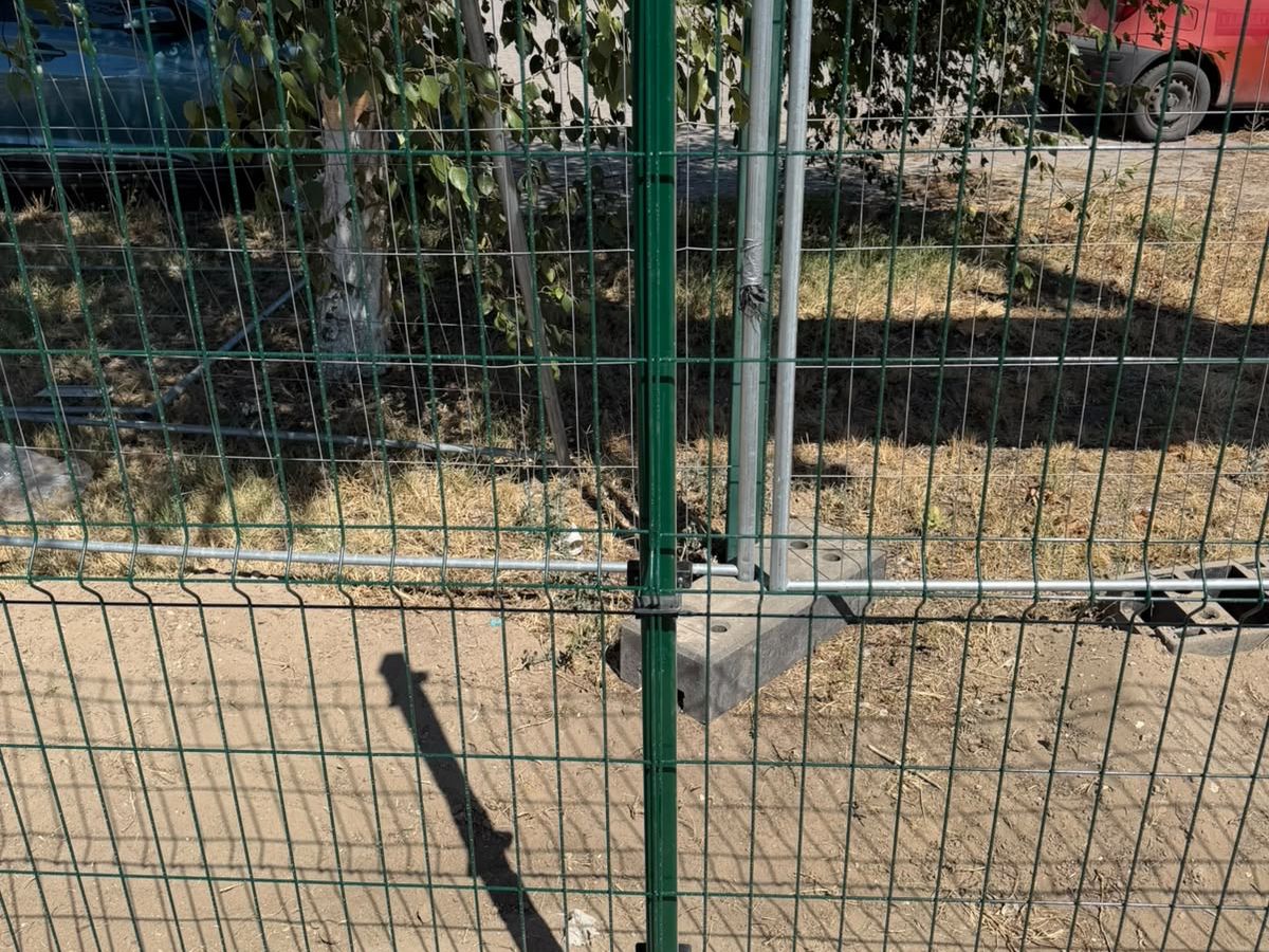 Zöld 3D táblás kerítés oszlopa és bilincsei közelről, beton lábazaton